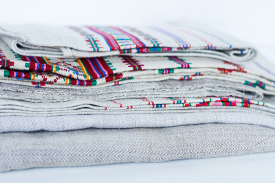 A stack of woven linen towels with embroidery, tra