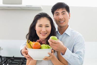 年轻夫妇在厨房里拿着装满水果的碗