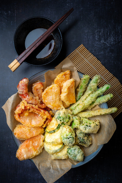 平铺一层准备好的日本蔬菜天妇罗配生姜姜蘸酱，黑色底色配拷贝空间，垂直摆放