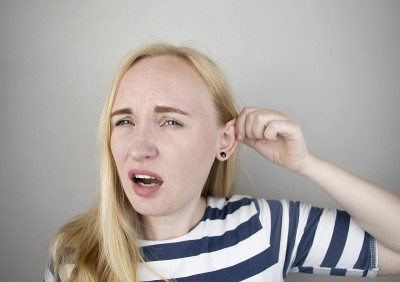 一个女人忍受着耳朵疼痛。中耳炎、耵聍塞、耳疖或三叉神经痛引起的耳道疼痛