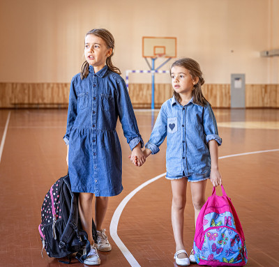 空空的学校体育馆里背着书包的小女孩们。