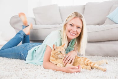 快乐的女人和猫躺在地毯上