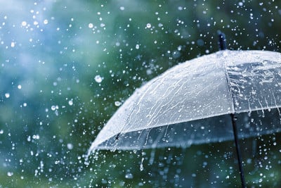透明的伞在雨点的映衬下溅起水滴。雨天的概念。
