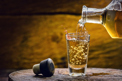 金色的朗姆酒和酒瓶。把酒精倒进小玻璃杯里的瓶子。巴西出口型饮料