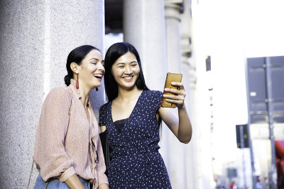 快乐的中国亚洲女友在户外玩手机