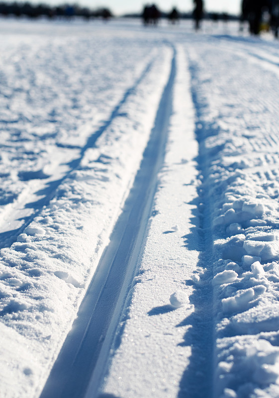 在一个阳光明媚的冬日，在雪地上越野滑雪道和小道