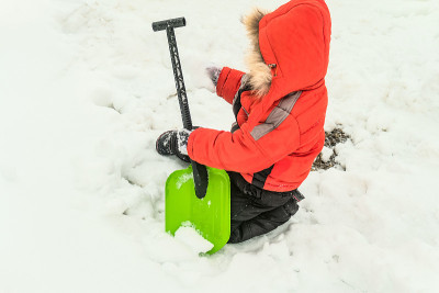 小男孩在一堆雪中玩雪铲。冬季活动。