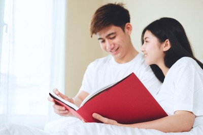 亚洲夫妇看书，买人寿保险，买房子，看结婚照。
