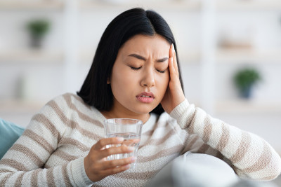 在家里遭受头痛或偏头痛的年轻亚洲妇女