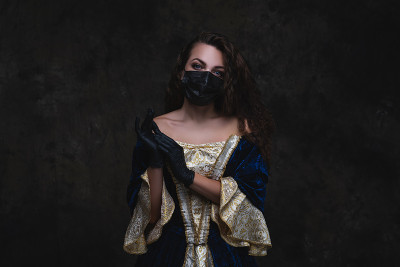 美丽的女人在文艺复兴时期的服装，面具和手套在抽象的黑色背景