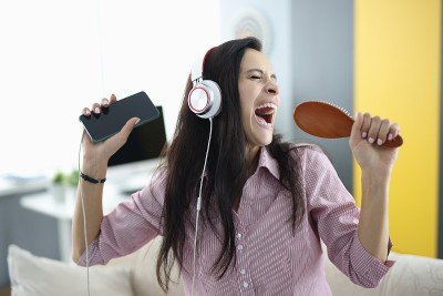 手持耳机和梳子的女子深情歌唱