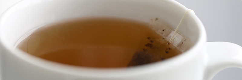 白杯子里煮好的新鲜茶包从边上垂下来