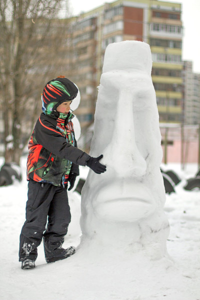 男孩在堆冬天的雪人。一个不寻常的雪人在多雪的冬天户外