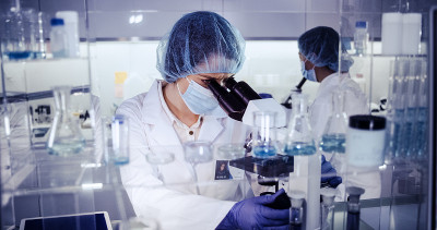 研究DNA突变的多种族女性团队。在防护服中使用显微镜