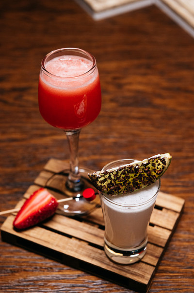 木板上放着两杯酸橙和草莓鸡尾酒