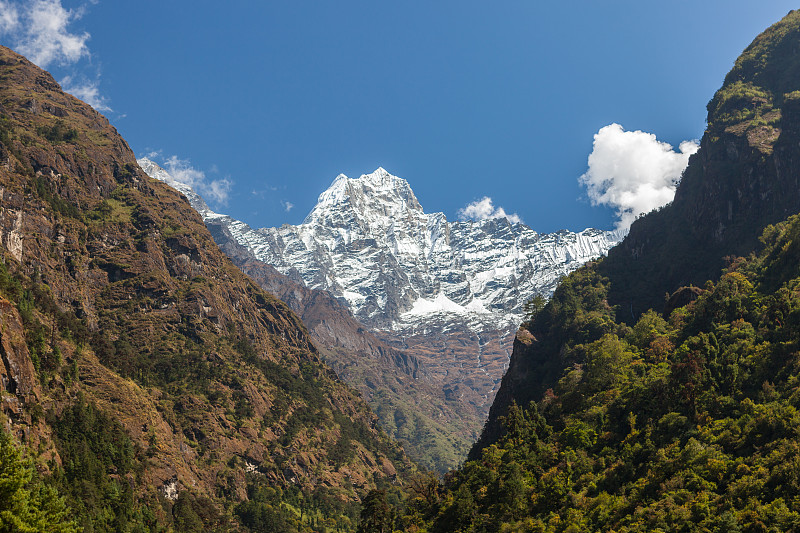 尼泊尔，喜马拉雅山，萨加玛塔国家公园，在岩石山和树木丛生的小山之间的雪山顶峰。