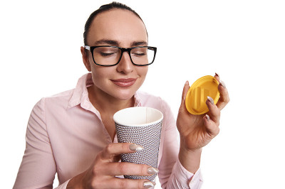 年轻女子享受着外卖纸杯里热饮的香味。孤立在白色背景上。本空间