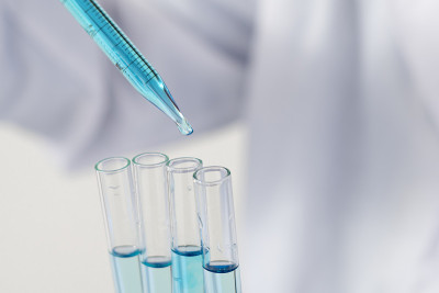 生物化学实验室研究，科学家或医务人员在实验室工作的玻璃设备上，穿着实验室大褂，拿着带有彩色液体的使用