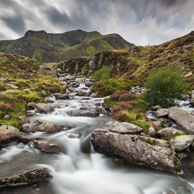 秋天，在斯诺登尼亚的Llyn Ogwen和Llyn Idwal附近，一条河流顺着山脉流下的穆迪景观图