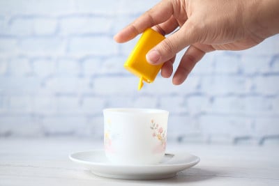 年轻女性往茶里放人造甜味剂，