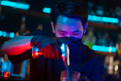 亚洲男子调酒师制作特别的鸡尾酒为顾客服务。