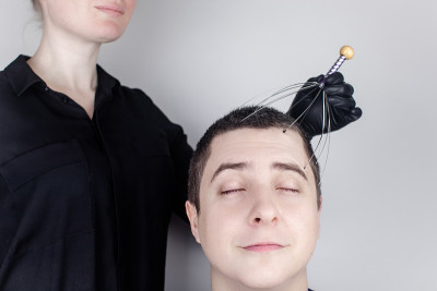 一个男人在沙龙里用毛细管按摩器做头部按摩。客户的脸上流露出放松和喜悦。抗压力按摩的概念和由按摩师提供