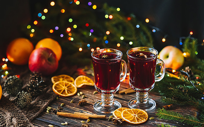 在玻璃杯中放入热葡萄酒，配上橙子片、苹果和香料，装饰圣诞节