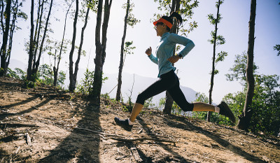 年轻女子越野跑者在日出热带森林山顶
