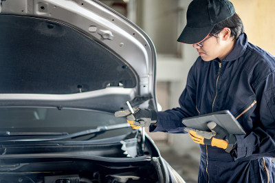 亚洲汽车技师用平板电脑检查汽车