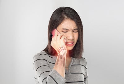 年轻的亚洲女子拿着手机感到肌肉手腕疼痛