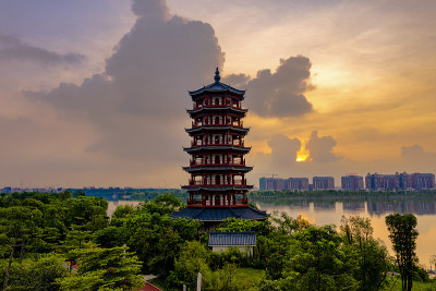 清晨的阳光照在公园湖边的古塔上