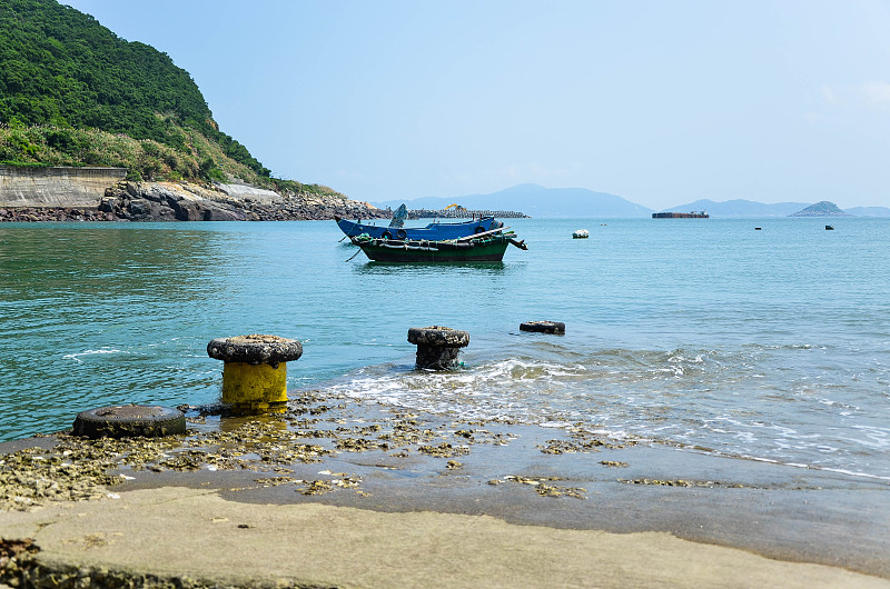 码头通向大海，远处停泊着小船。