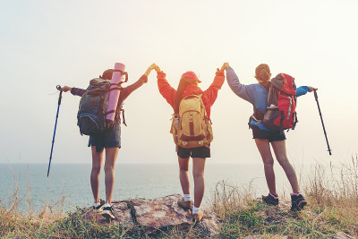 团体朋友团队亚洲年轻女性徒步旅行冒险与背包在山在日落。