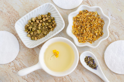 小白碗，里面有化妆(按摩、清洁)精油、干洋甘菊和金盏花。天然护肤，自制spa，美容护理配方。平躺