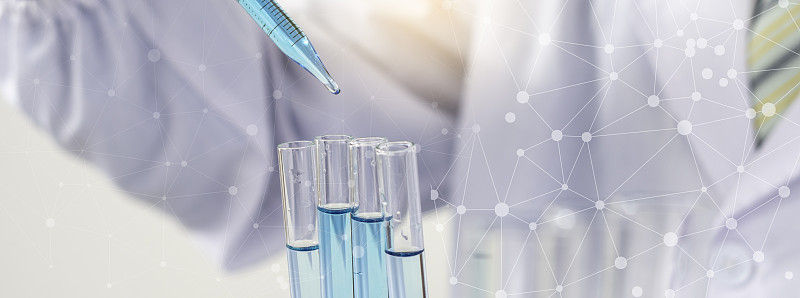 生物化学实验室研究，科学家或医务人员在实验室工作的玻璃设备上，穿着实验室大褂，拿着带有彩色液体的使用