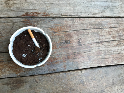 一支香烟放在装满咖啡渣的白色陶瓷烟灰缸里