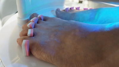 脚Spa。在水疗店的肥皂水机里，女人光脚按摩。女人的脚进入脚浴在热水手持式。在水疗沙龙用脚油按摩。放