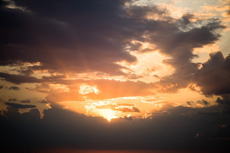 暴风雨戏剧性的天空背景与黄色、红色和橙色的云。日落地平线。海滩上的风暴