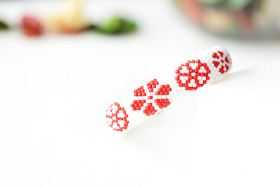 白色串珠手镯与红色花朵印花近距离