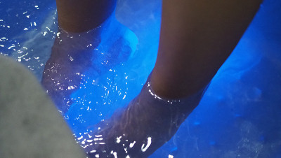 脚Spa。在水疗店的肥皂水机里，女人光脚按摩。女人的脚进入脚浴在热水手持式。在水疗沙龙用脚油按摩。放