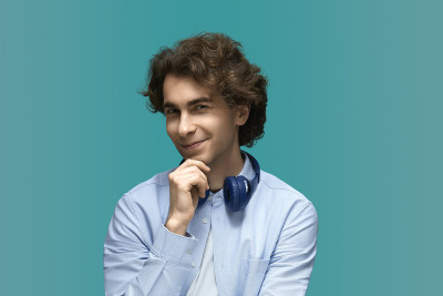 狡猾的人。一个年轻漂亮的男子的肖像穿着白色t恤和蓝色衬衫在蓝色耳机。一边想一边握紧拳头，看着镜头