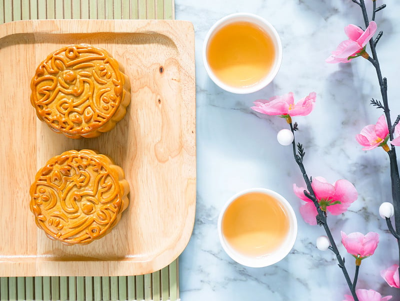 木盘上放着月饼，配着几杯茶