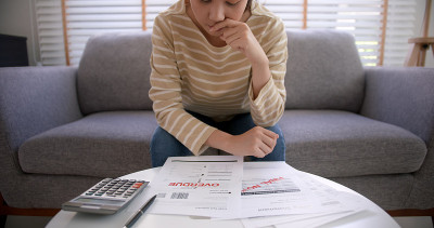 沮丧疲惫的年轻的亚洲悲伤的女人们坐在家里沙发沙发上思考担心税收费用储蓄问题逾期贷款逾期付款covid