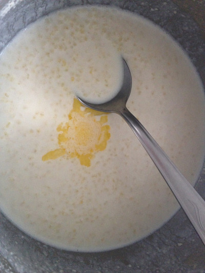 小米粥，牛奶和黄油在锅和勺子。