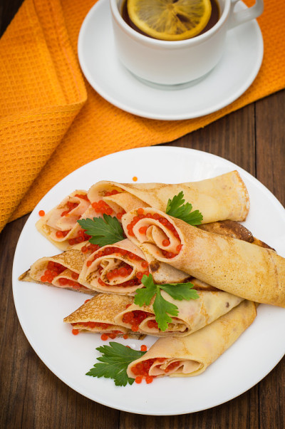红鱼子酱煎饼卷。俄罗斯菜。平的。Maslenitsa。木制背景。前视图。特写镜头