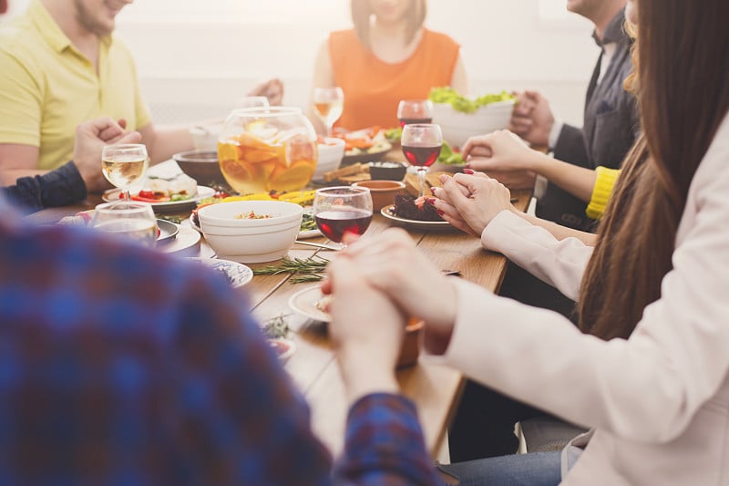 朋友们在节日的餐桌上付饭钱，拿着汉斯