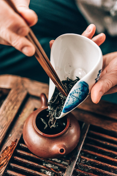 中国茶道，男子将茶叶倒入茶壶中冲泡