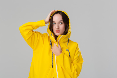 微笑的黑发女孩穿着黄色雨衣。准备好迎接坏天气吧。