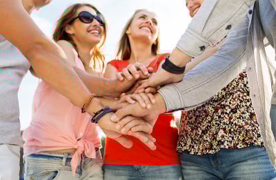 close up of happy friends with  hands on top