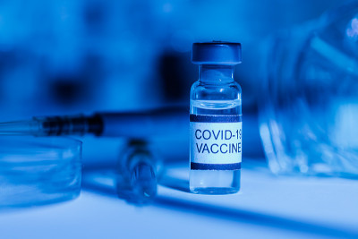 配有试管支架、COVID-19疫苗瓶、注射器、移液管、防护眼镜和培养皿的实验台，蓝光环境